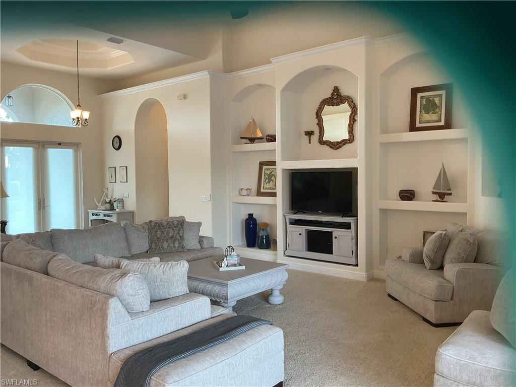 Carpeted living area featuring built in features, french doors, and a raised ceiling