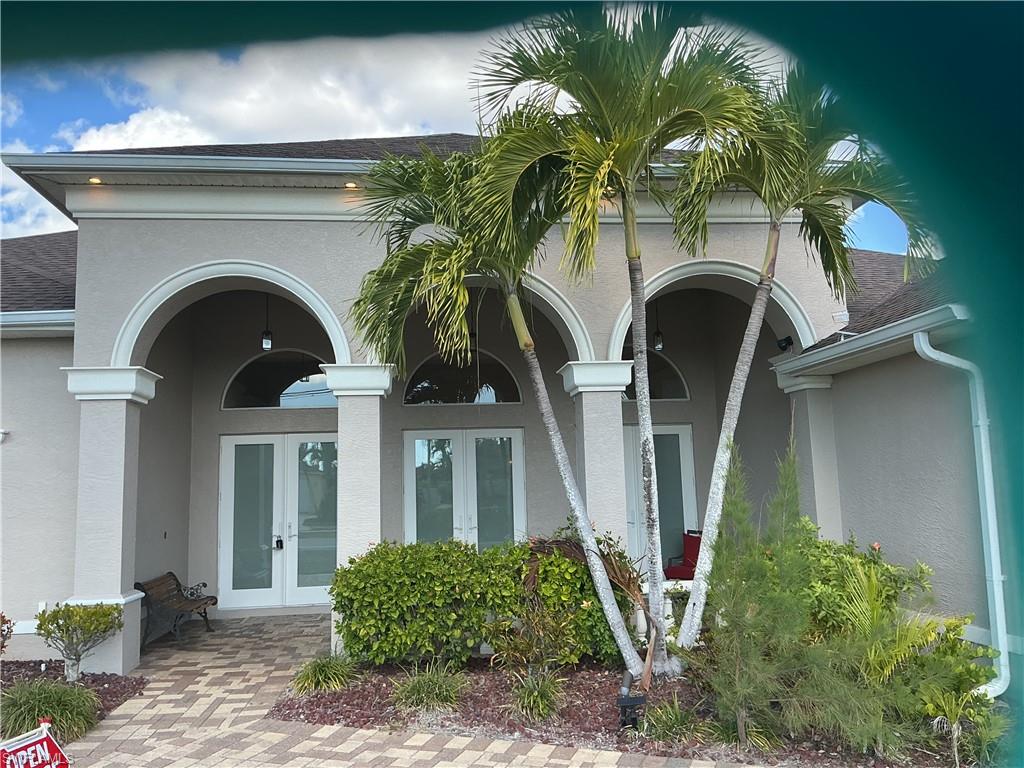 View of exterior entry featuring french doors, stucco siding, and roof with shingles