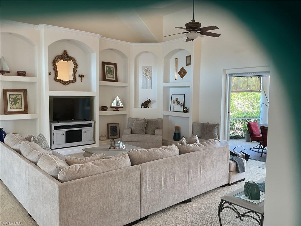 Living area featuring built in shelves, a ceiling fan, and carpet floors