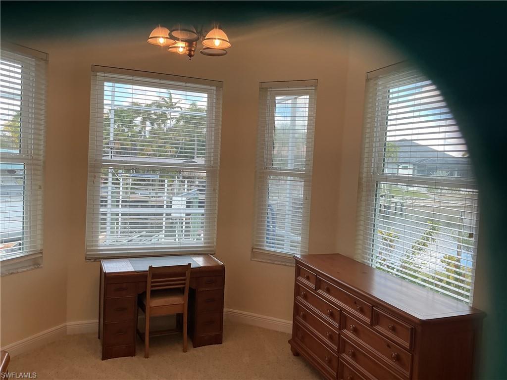 Unfurnished office with healthy amount of natural light, light colored carpet, and hanging lights