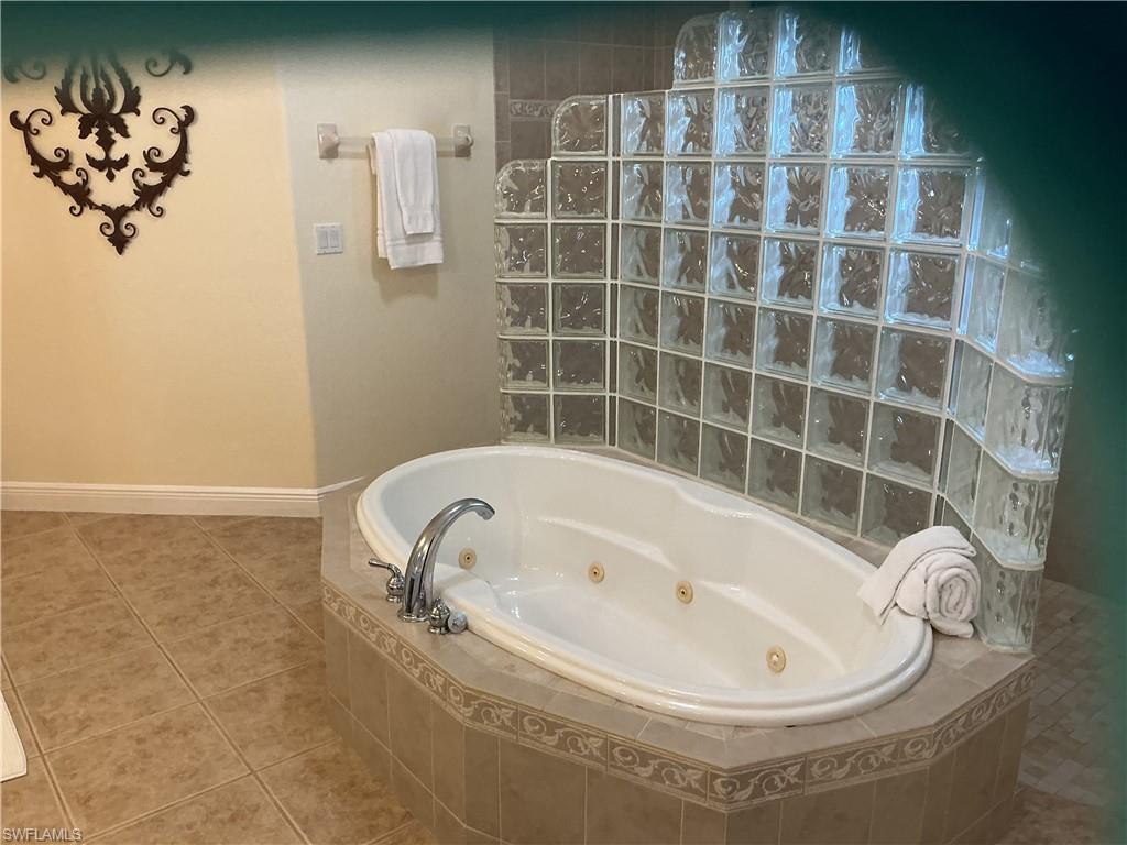 Bathroom with a tub with jets, tile patterned flooring, and walk in shower
