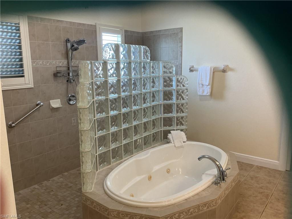 Bathroom with walk in shower, a tub with jets, and tile patterned flooring