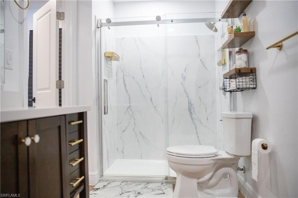 Full bath with vanity, a marble finish shower, and light marble finish flooring