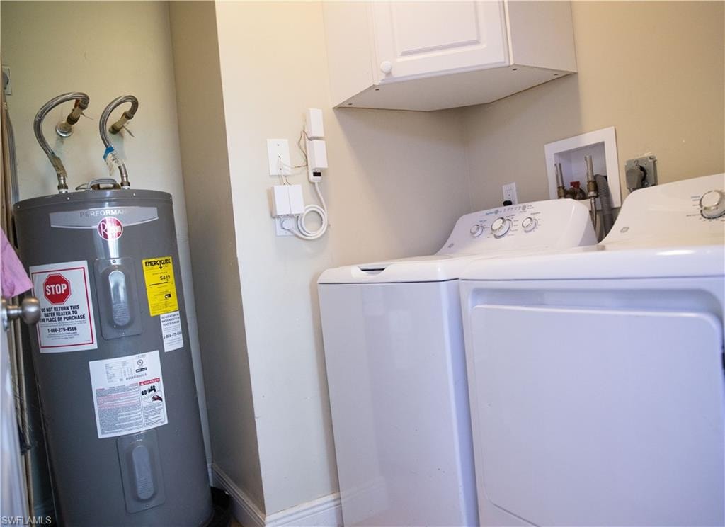 Laundry room featuring electric water heater, cabinet space, and washer and dryer