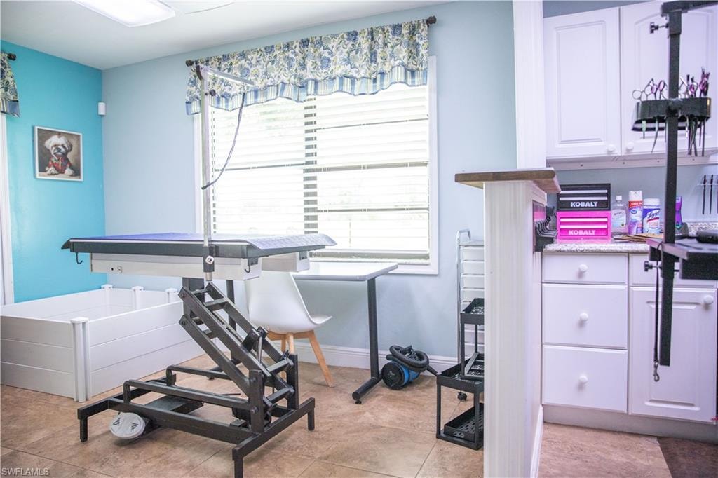 Exercise room featuring baseboards and light tile patterned floors