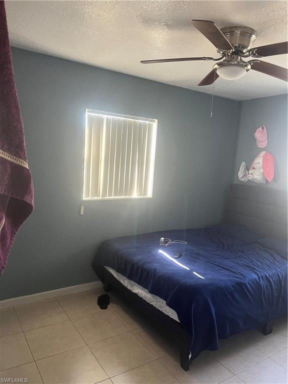 Bedroom featuring a textured ceiling, ceiling fan, and light tile patterned floors