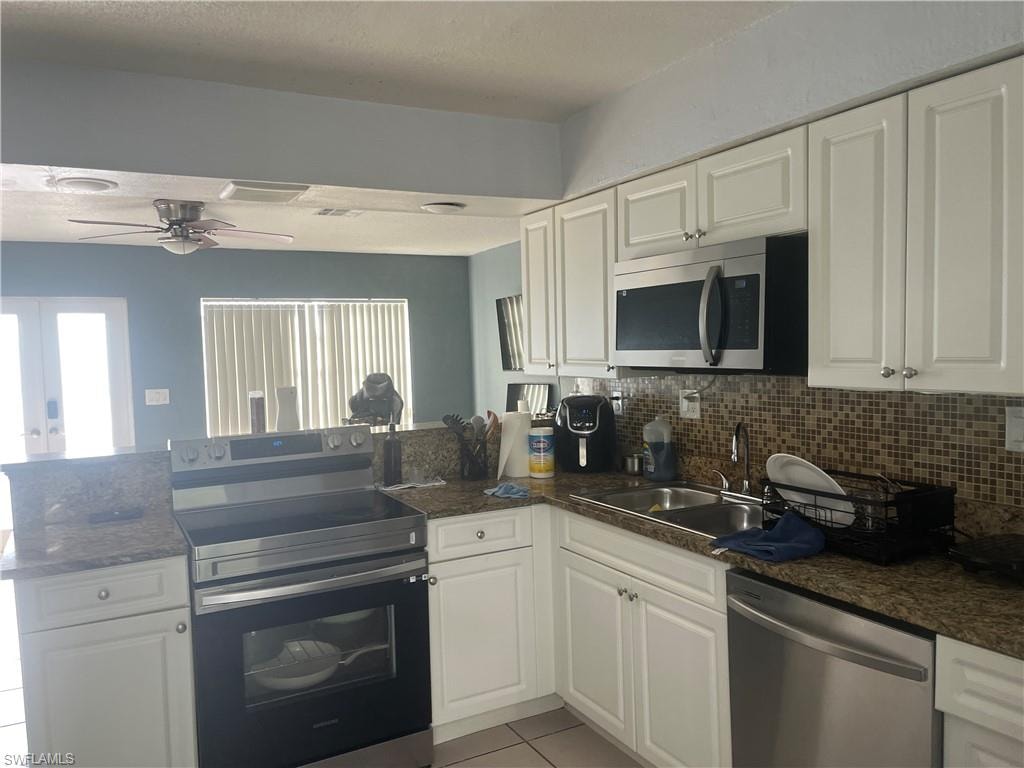 Kitchen featuring appliances with stainless steel finishes, a peninsula, white cabinets, and tasteful backsplash