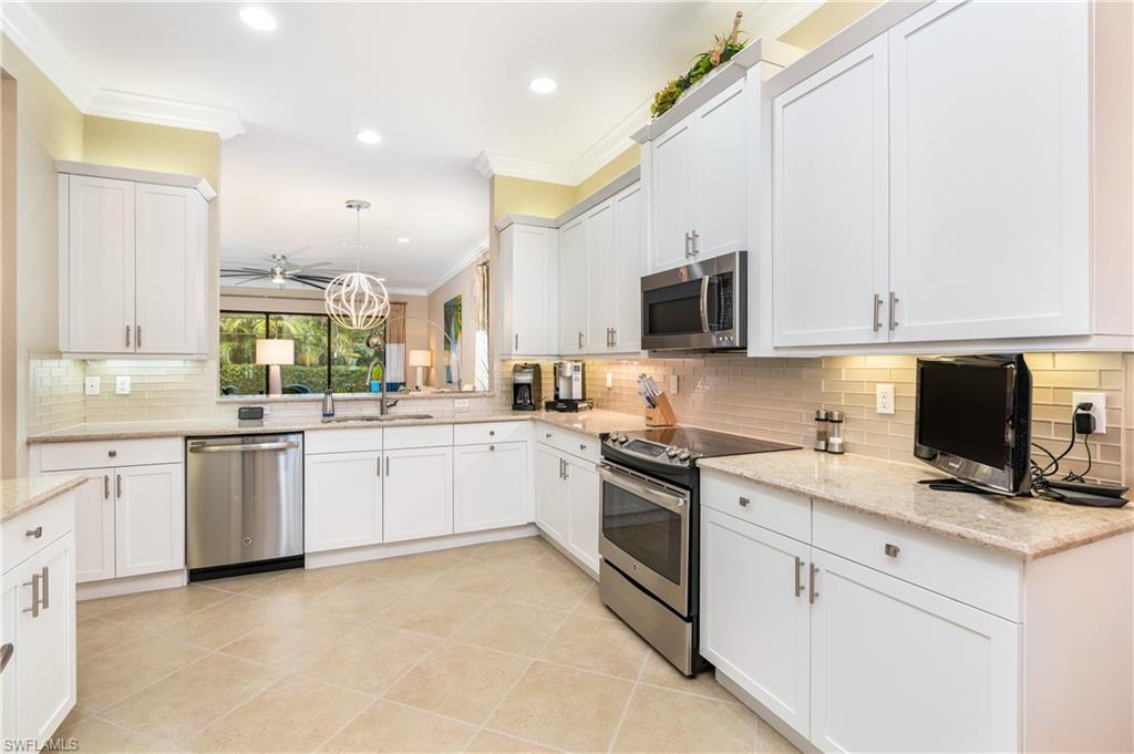 Kitchen featuring ornamental molding, appliances with stainless steel finishes, white cabinetry, pendant lighting, and backsplash