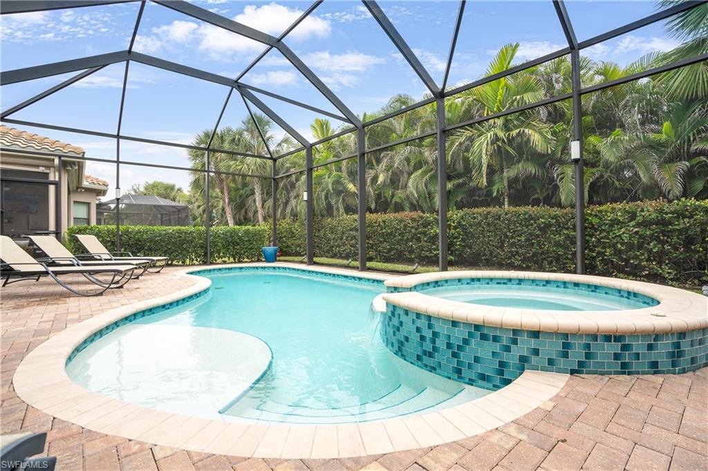 View of swimming pool with a sunroom, a pool with connected hot tub, glass enclosure, and a patio area