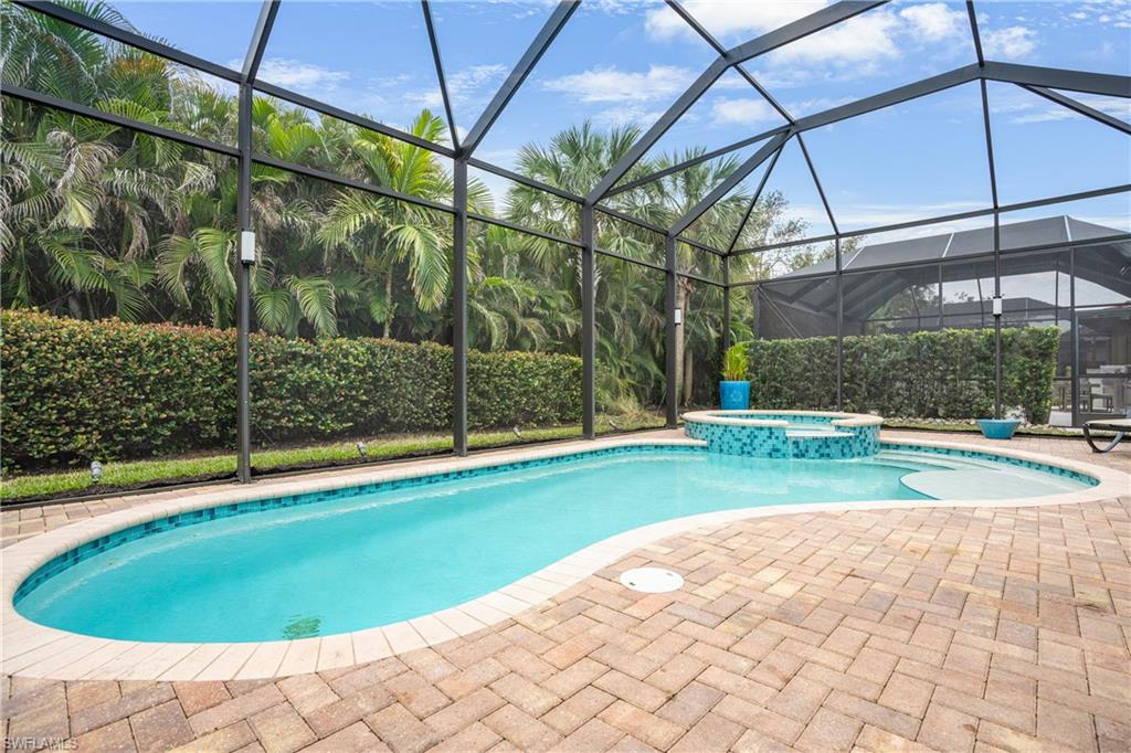 View of pool with a pool with connected hot tub, a sunroom, glass enclosure, and a patio