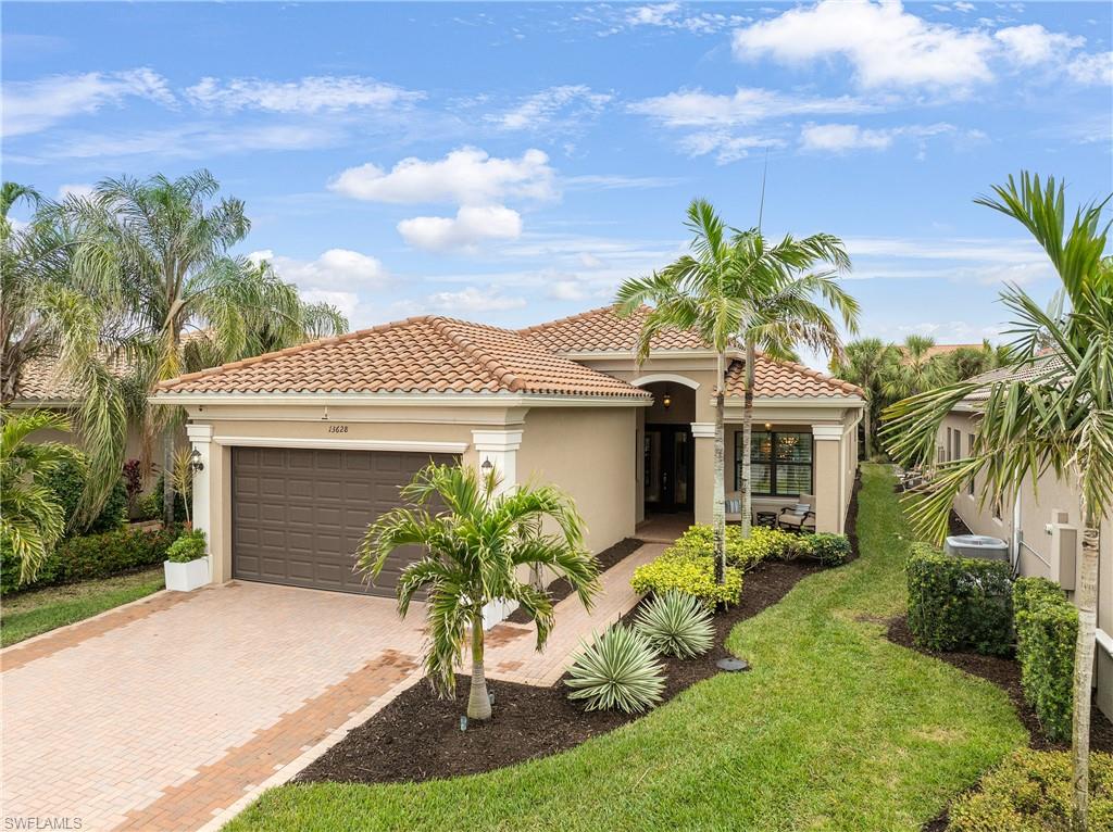 Mediterranean / spanish house with stucco siding, a tiled roof, an attached garage, and decorative driveway