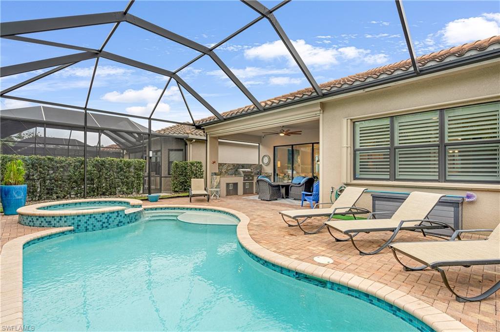 View of pool featuring a sunroom, a lanai, a pool with connected hot tub, and a patio
