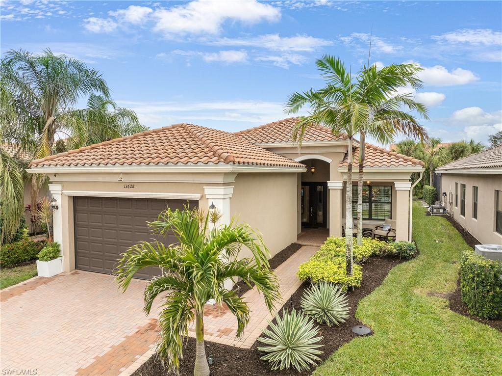 Mediterranean / spanish-style home with stucco siding, a garage, decorative driveway, a tile roof, and a front lawn