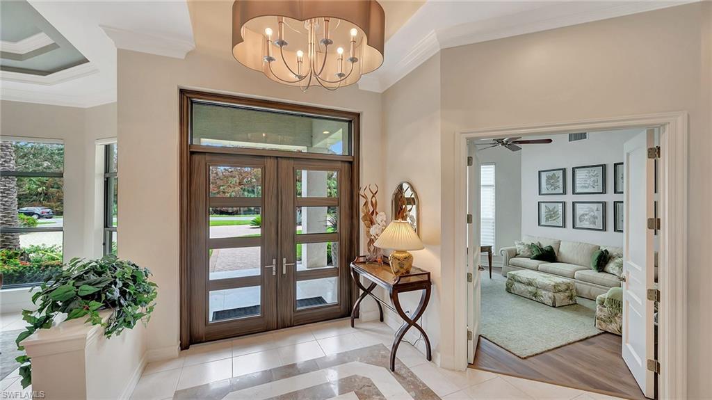 Foyer entrance with ornamental molding, french doors, a wealth of natural light, and light hardwood / wood-style floors