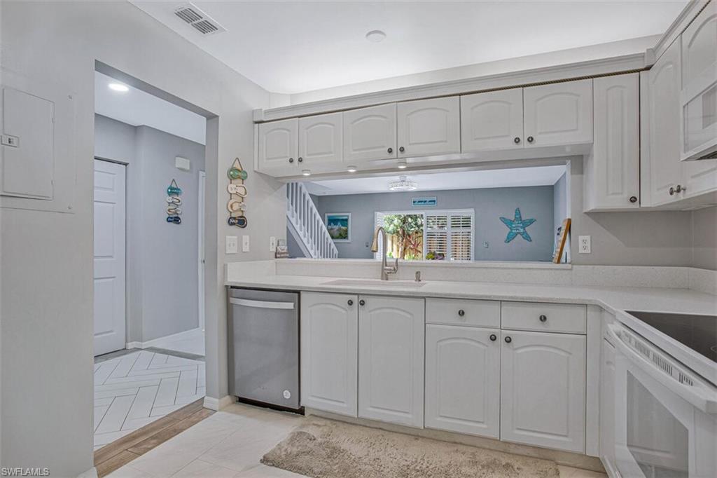 Kitchen with white appliances, white cabinets, electric panel, light tile patterned floors, and light stone countertops