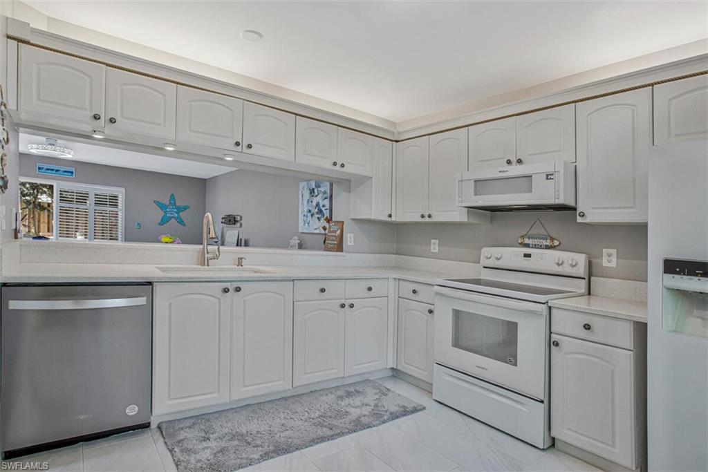 Kitchen with white appliances, white cabinets, and light stone countertops