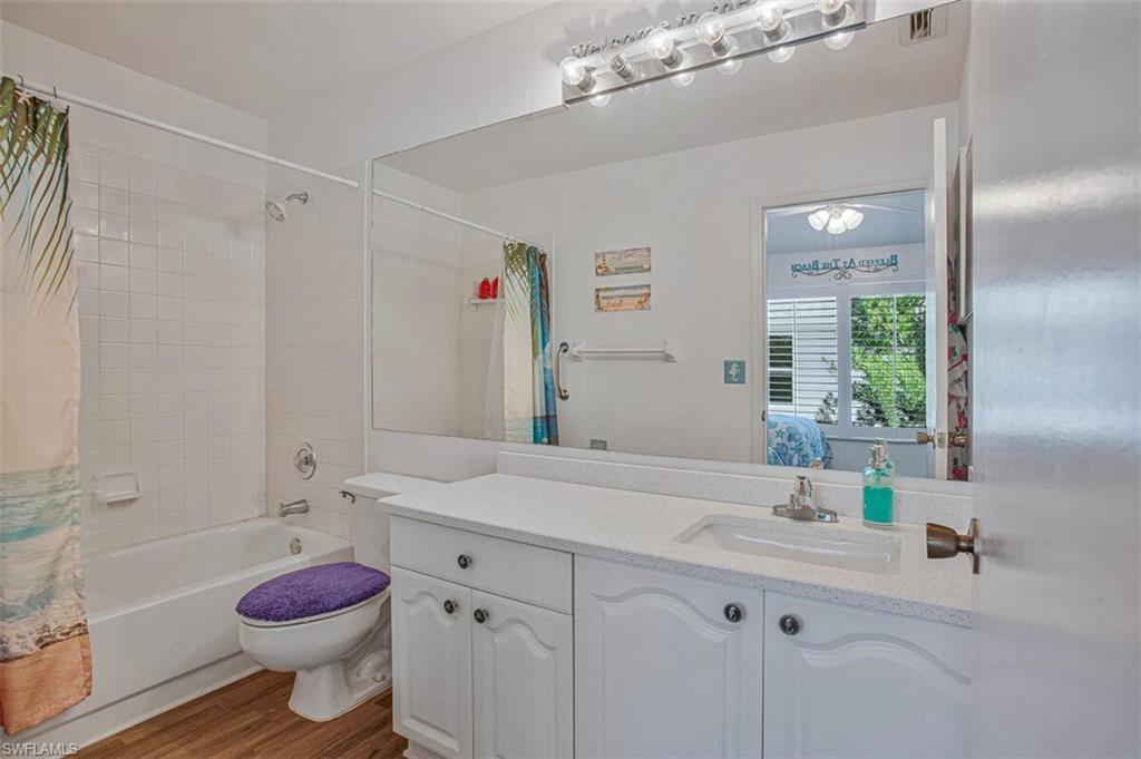 Ensuite bathroom featuring vanity, shower / bathtub combination with curtain, and wood finished floors