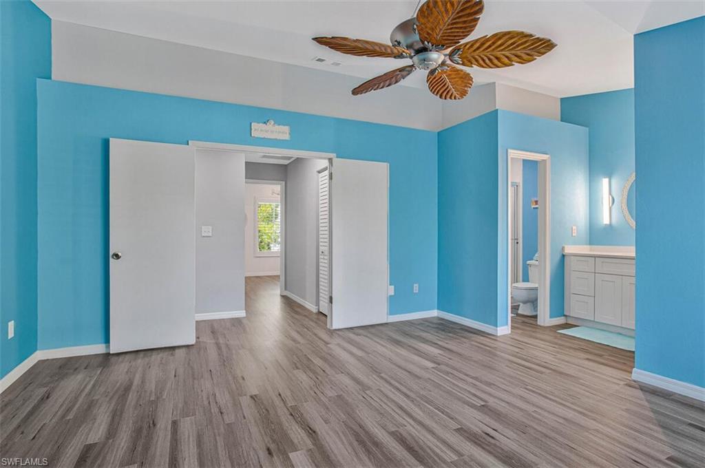 Unfurnished bedroom with light wood-type flooring, ceiling fan, and connected bathroom