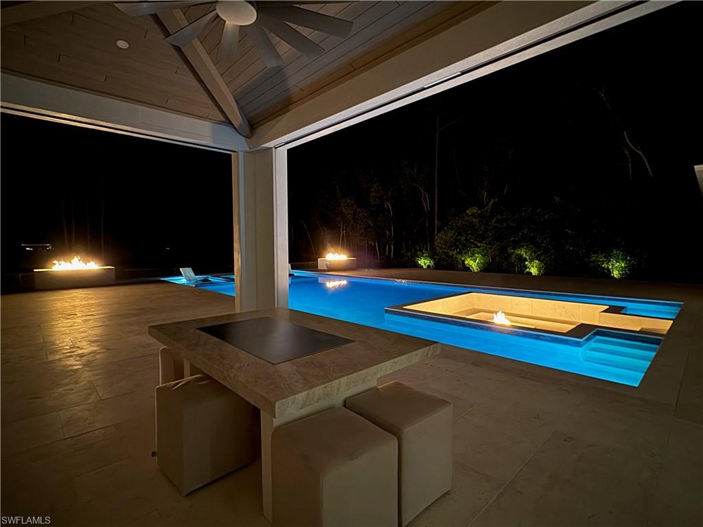 Pool at night with a patio area and an outdoor pool