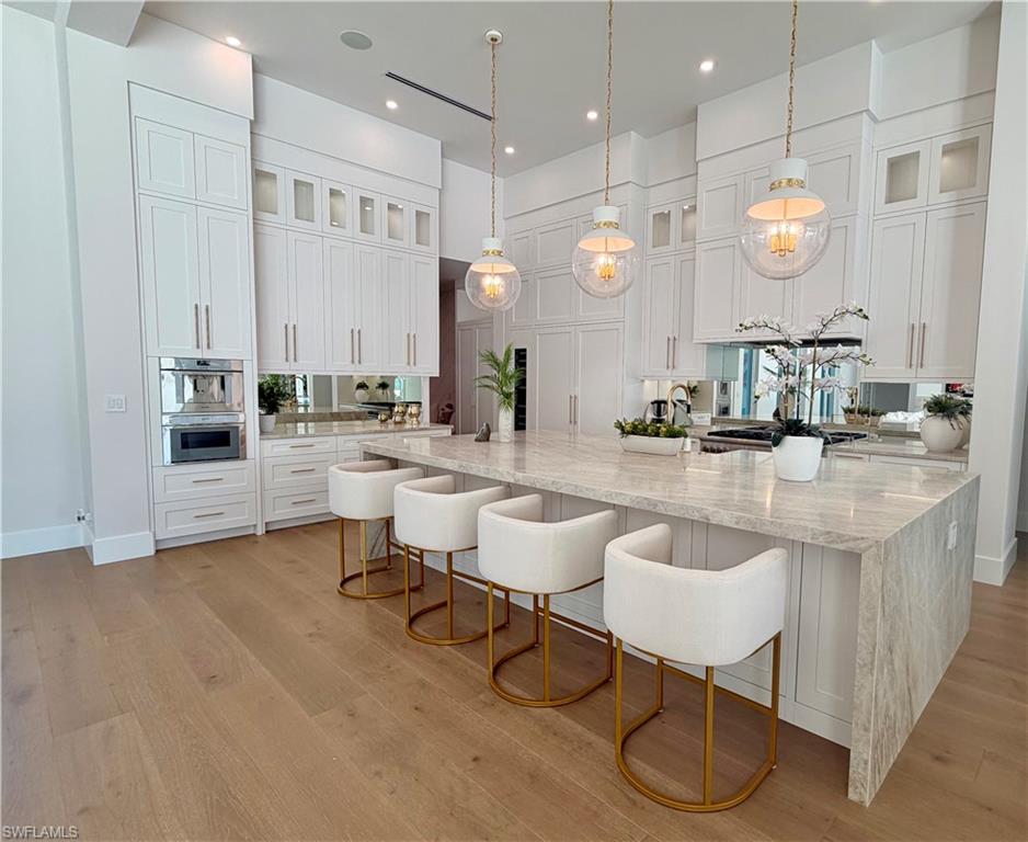 Kitchen featuring glass insert cabinets, light stone counters, white cabinets, and recessed lighting
