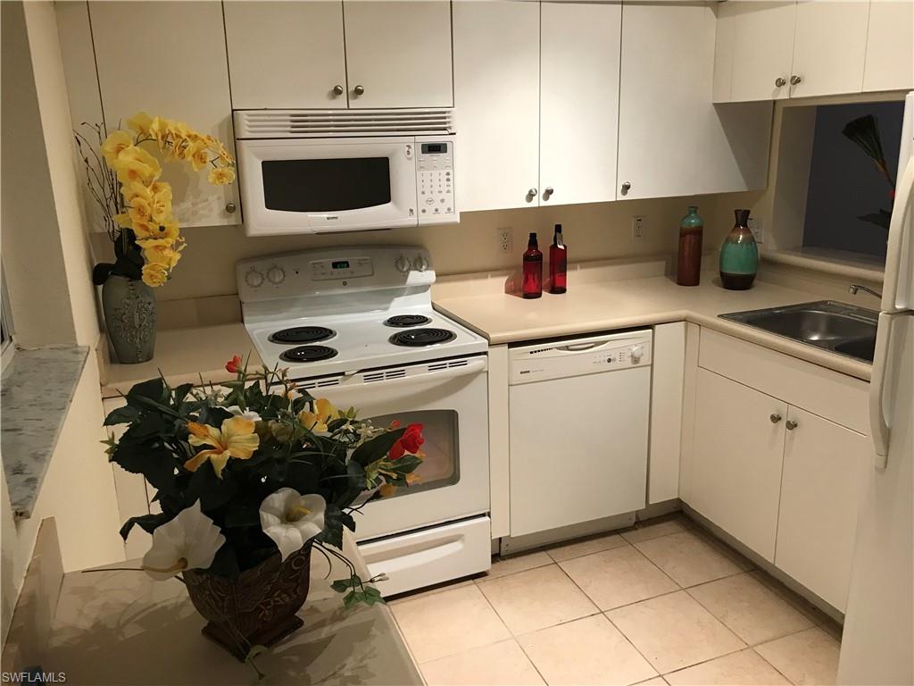 Kitchen featuring white appliances, light countertops, and white cabinets