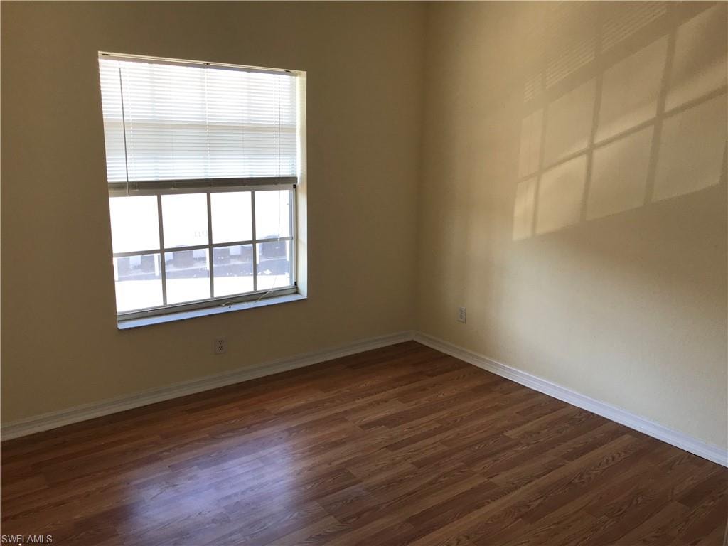 Unfurnished room featuring dark wood-style flooring and baseboards