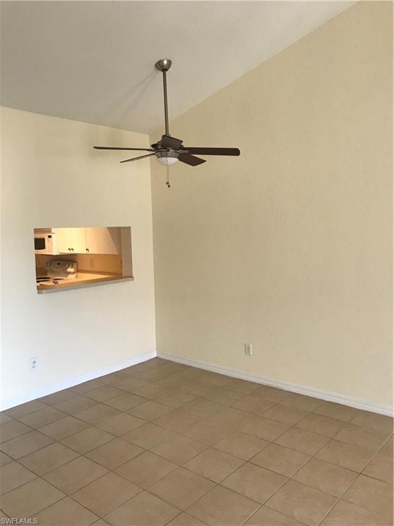 Tiled empty room with vaulted ceiling and a ceiling fan