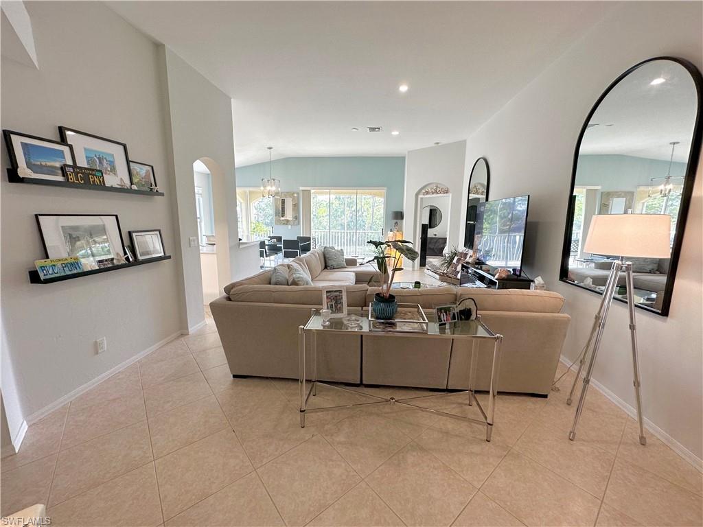 Living room with a chandelier, arched walkways, lofted ceiling, and light tile patterned floors