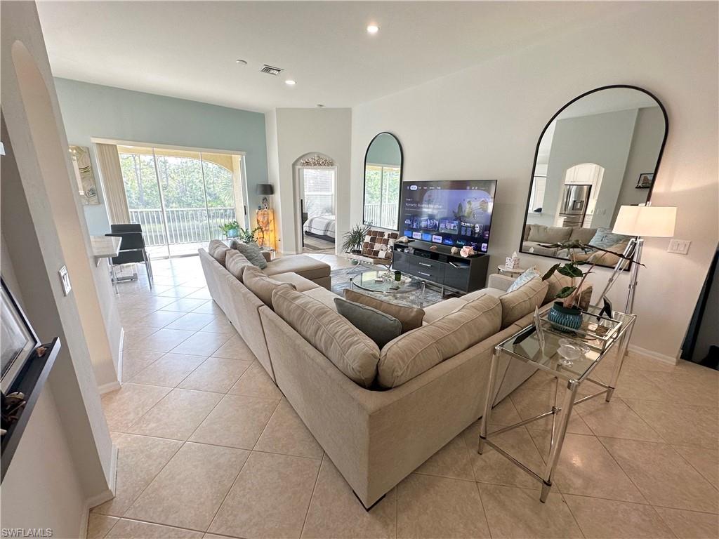 Living room with arched walkways, light tile patterned floors, healthy amount of natural light, and recessed lighting