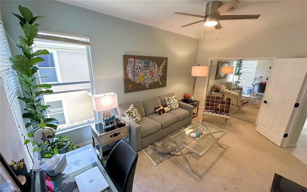 Carpeted living area featuring a desk and ceiling fan