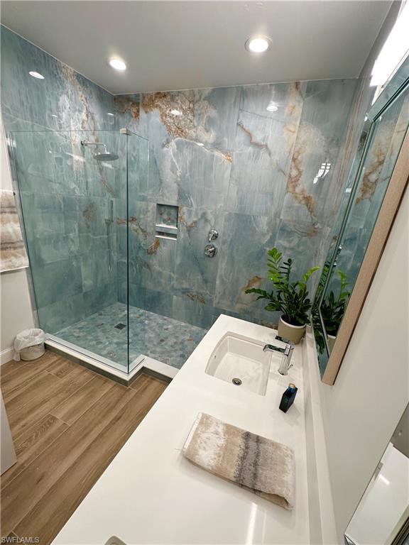 Bathroom with vanity, a marble finish shower, wood finished floors, and recessed lighting