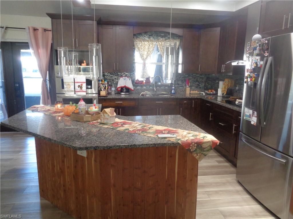 Kitchen with stainless steel appliances, granite countertops, dark brown cabinets, and backsplash