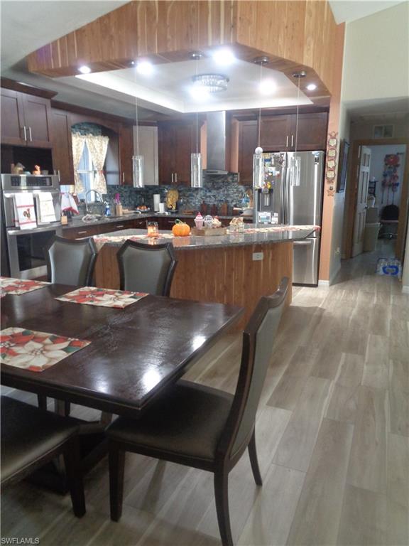 Dining room featuring a vaulted ceiling, light wood-style flooring, and recessed lighting