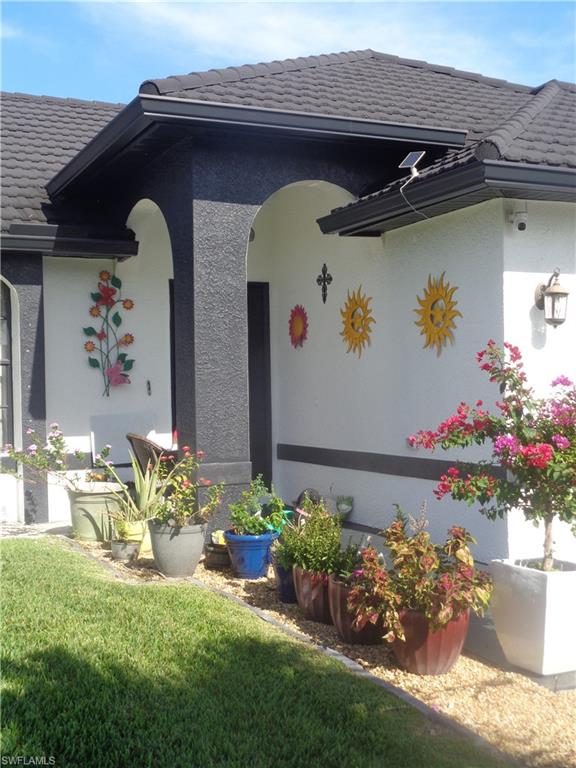 View of exterior entry featuring stucco siding, a lawn, and metal roof
