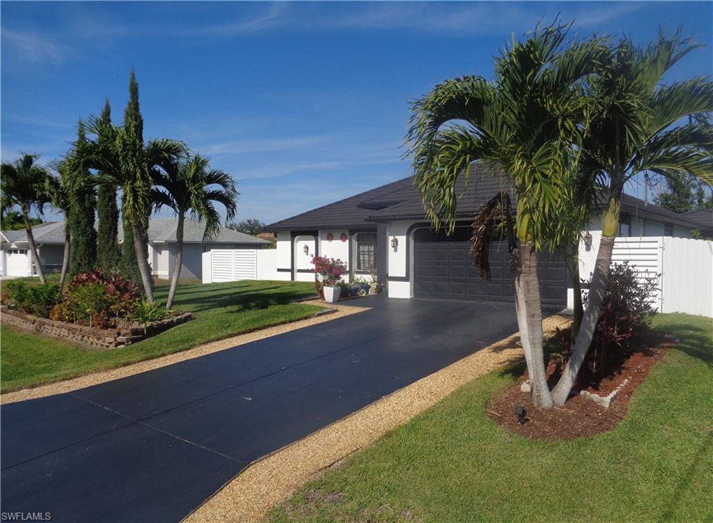 Right side view of single story home with a front yard, a garage, driveway, and stucco siding