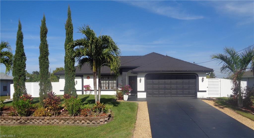 Front view of single story home with a garage, driveway, metal roof, and stucco siding