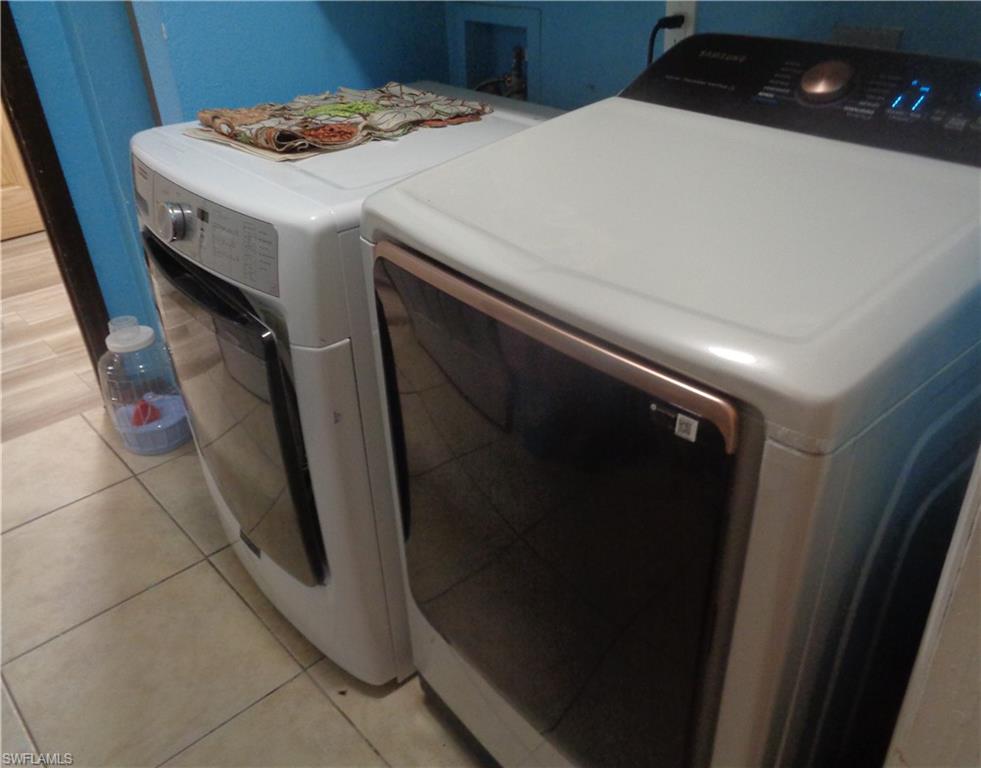Washroom featuring light tile patterned flooring and washer and dryer