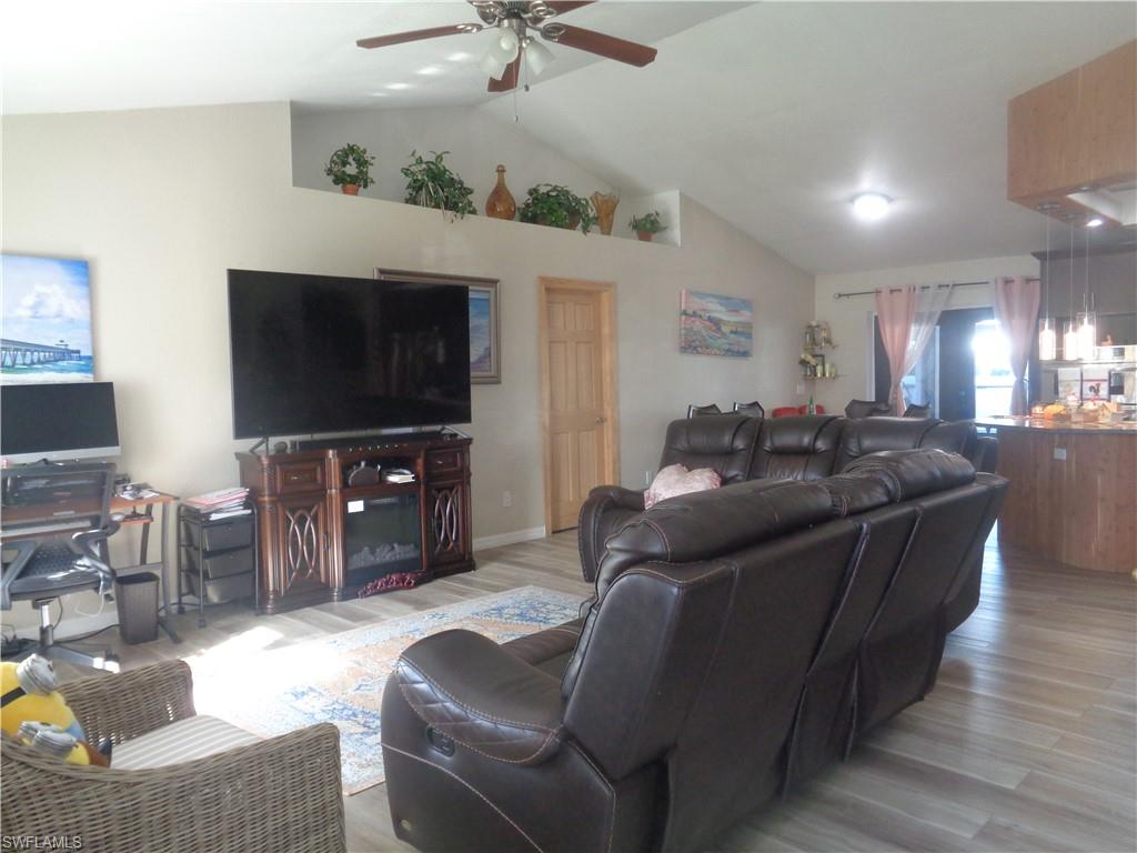 Living area featuring lvaulted ceiling, light wood-style flooring, and a ceiling fan