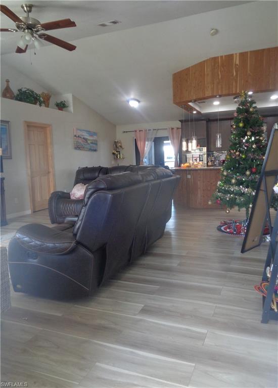 Living area featuring light wood-style flooring, a ceiling fan, and vaulted ceiling