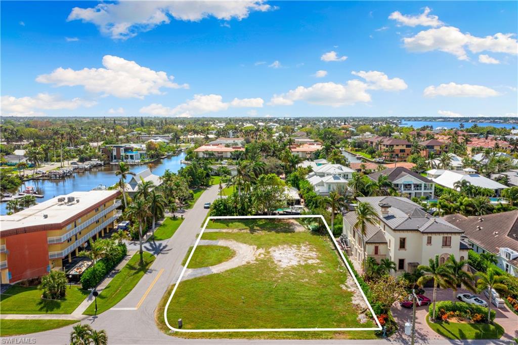 Aerial view of residential area with property boundaries highlighted and a nearby body of water