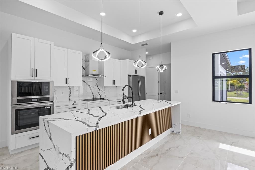Kitchen with white cabinetry, light stone counters, stainless steel appliances, and recessed lighting