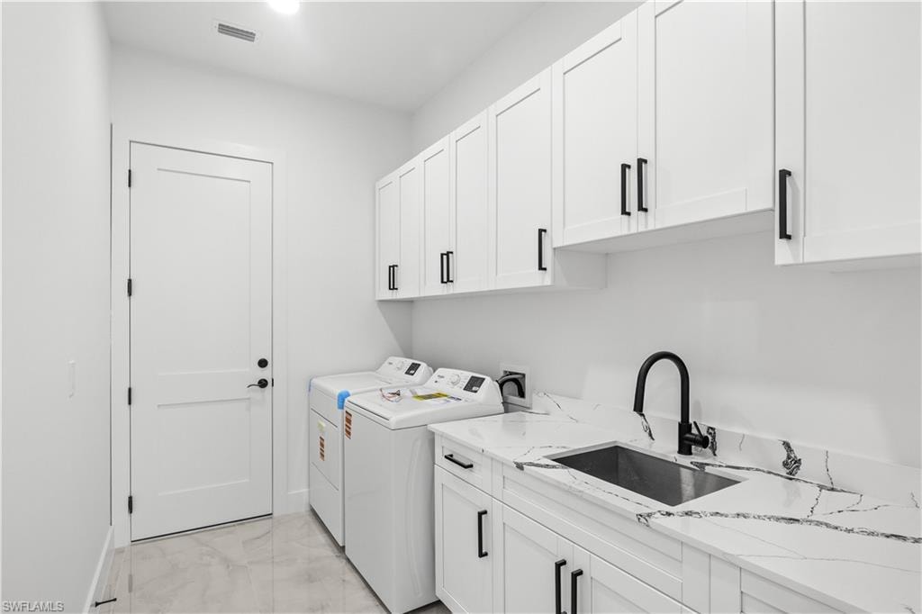 Laundry room with cabinet space, light marble finish flooring, and washing machine and clothes dryer