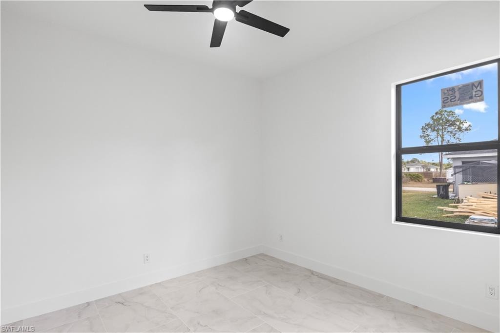 Spare room featuring light marble finish floors and ceiling fan
