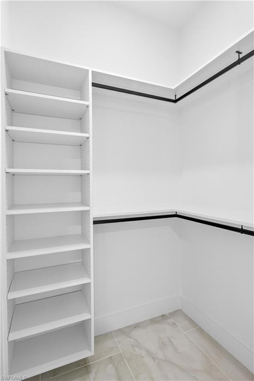 Spacious closet featuring light marble finish floors