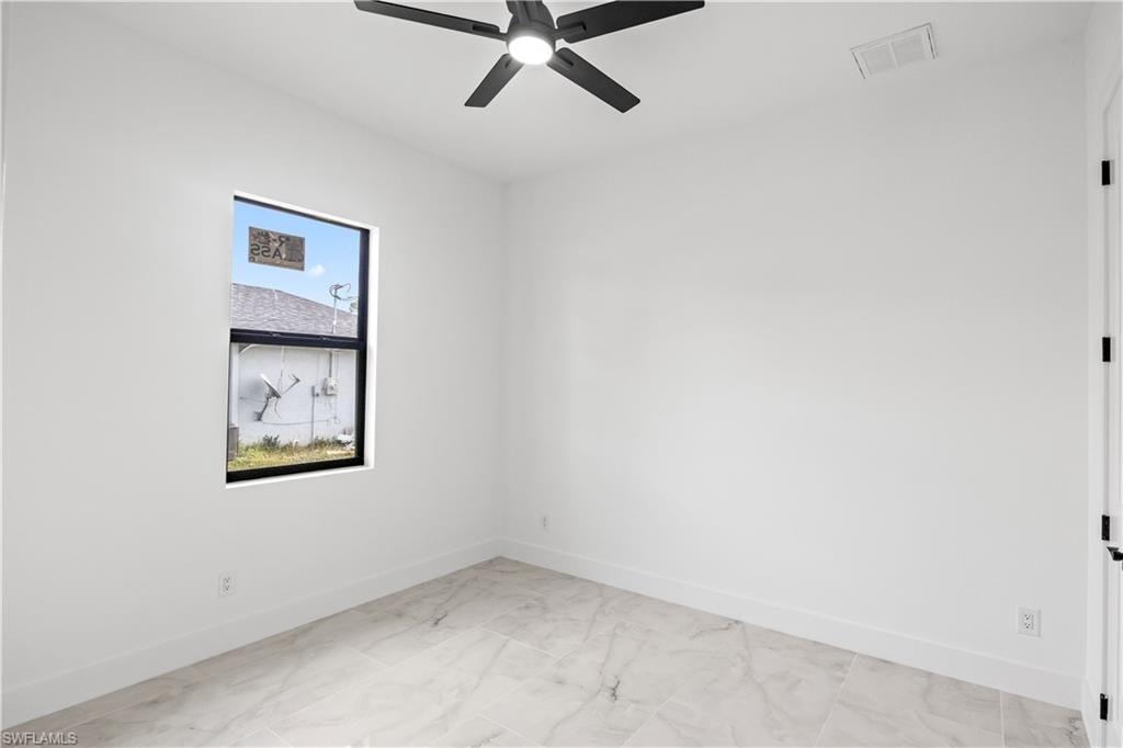 Spare room featuring a ceiling fan and light marble finish flooring