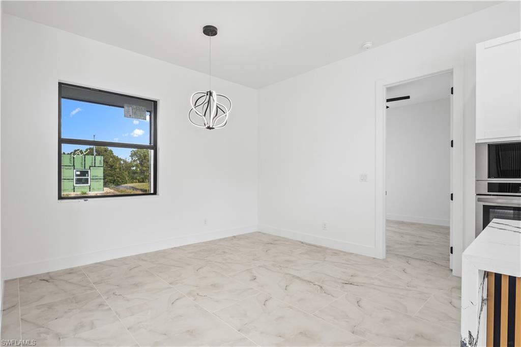 Unfurnished dining area featuring a chandelier and light marble finish floors
