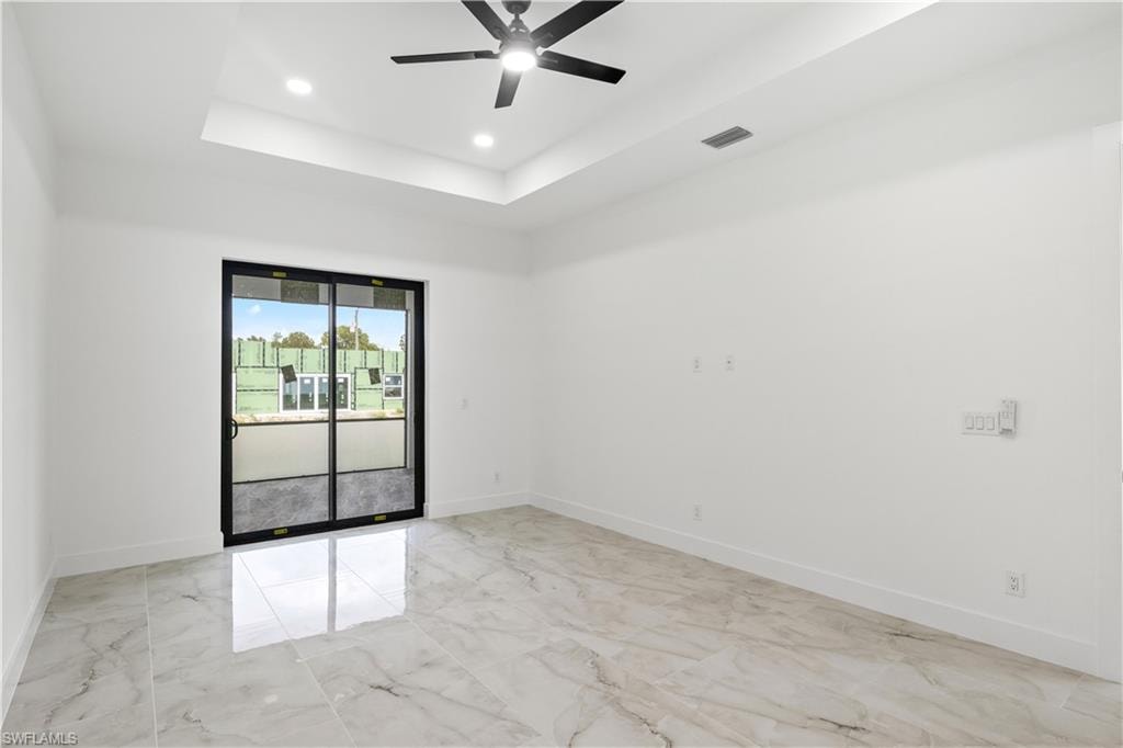 Spare room featuring light marble finish floors, a tray ceiling, a ceiling fan, and recessed lighting