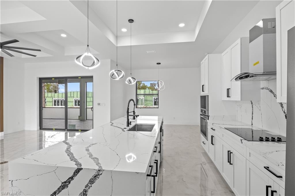 Kitchen featuring light stone countertops, healthy amount of natural light, decorative light fixtures, white cabinetry, and recessed lighting