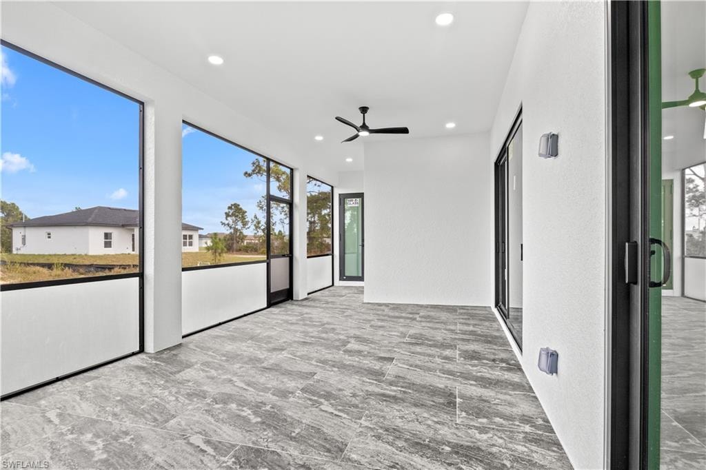 Unfurnished sunroom with a ceiling fan and recessed lighting
