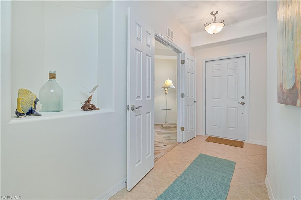 Foyer with light tile patterned flooring and baseboards